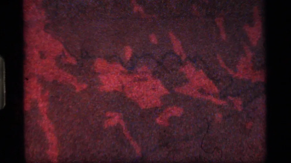 Red-toned 8mm frame showing an abstract map-like detail that appears to relate to the surrounding landscape.