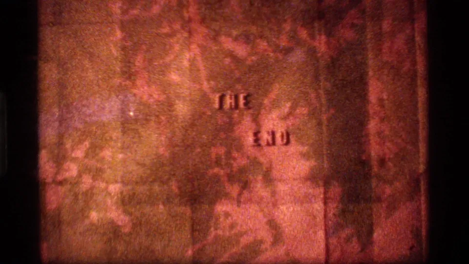 1977 8mm end-title frame from Sapphire Lake, Montana, with "THE END" visible through warm grain and flicker.