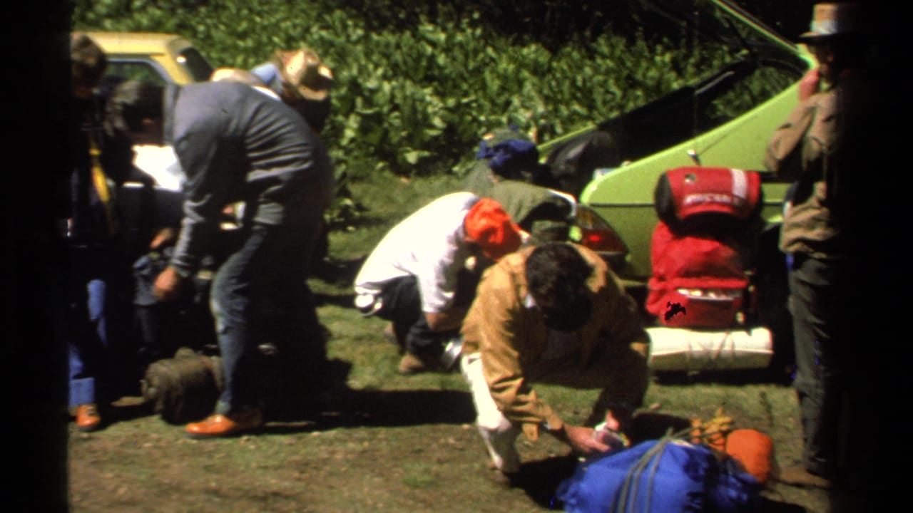 Lake Tahoe 1978 frame with adults in casual clothes arranging hiking or camping gear near a green vintage car.
