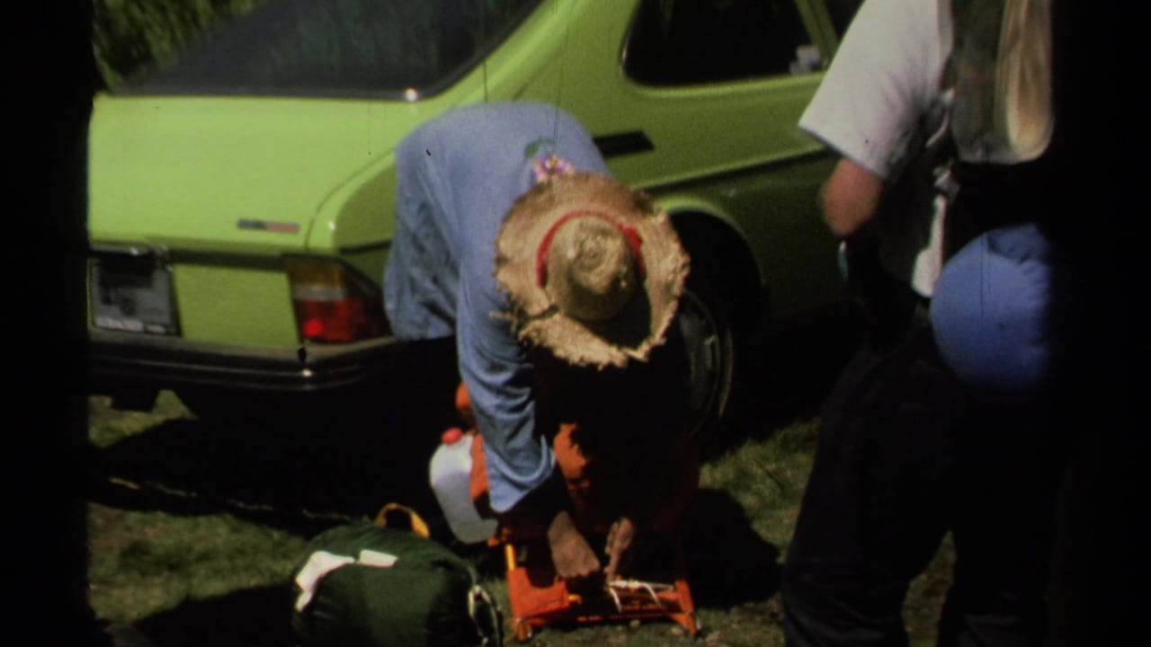 At Lake Tahoe in 1978, a man in a straw hat organizes orange camping gear while others stand near a lime-green car.