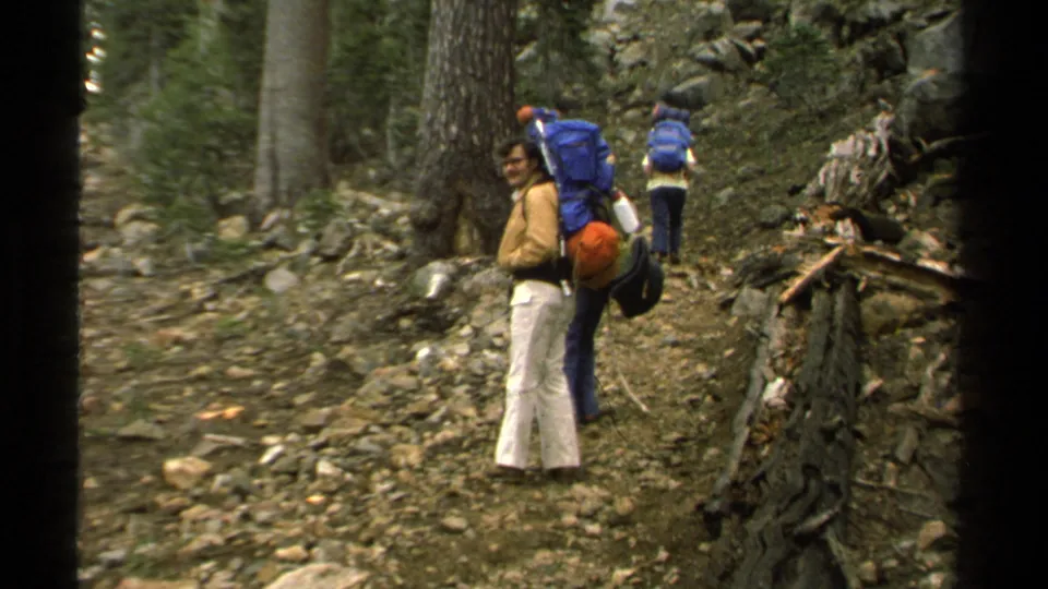 1978 Lake Tahoe 8mm frame showing a hiker with a large blue pack looking back on a rocky forest path.