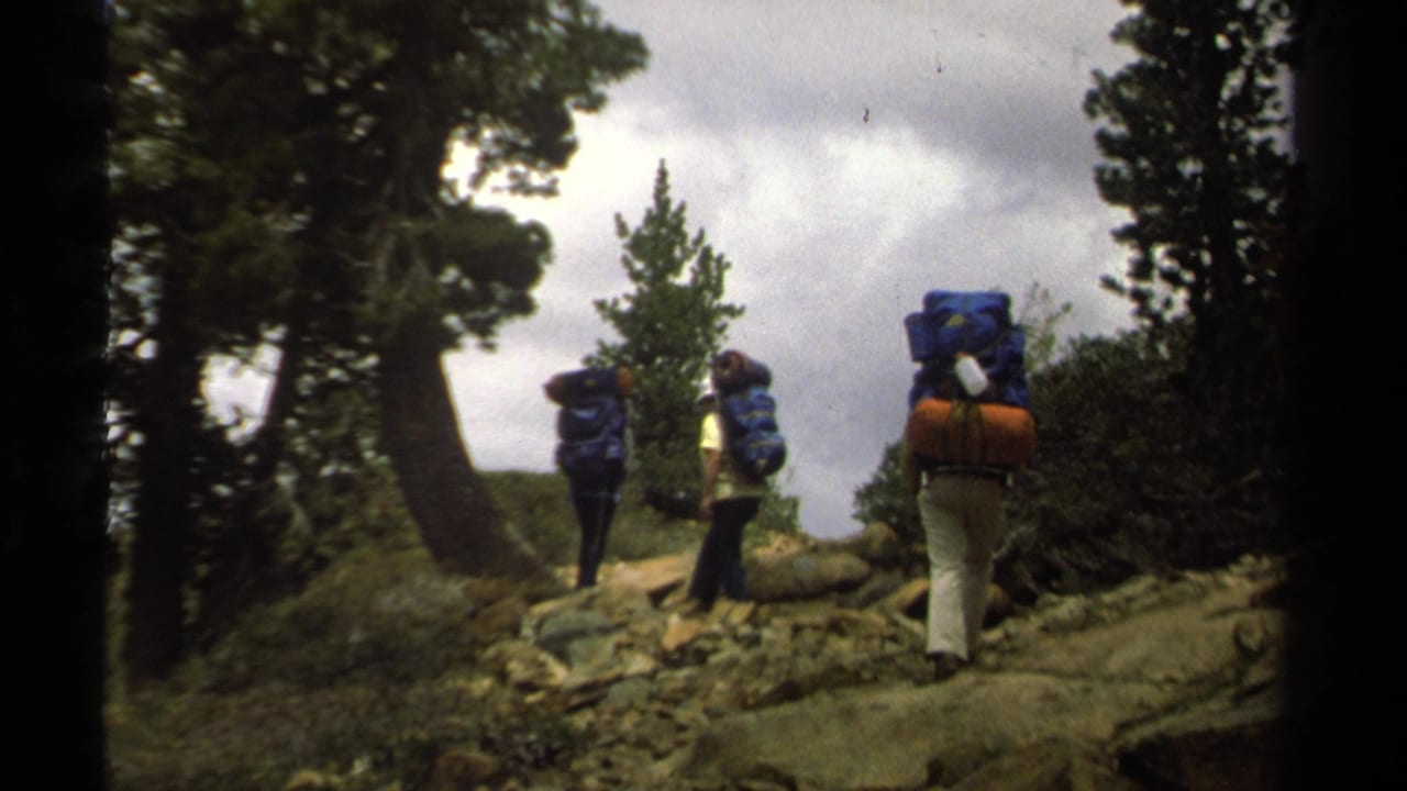 A small group of backpackers walks through a rugged wooded Lake Tahoe landscape, filmed on 8mm in 1978.