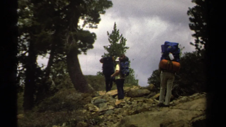 Backpackers climb a rocky Lake Tahoe-area trail under cloudy skies in archival 8mm footage from 1978.