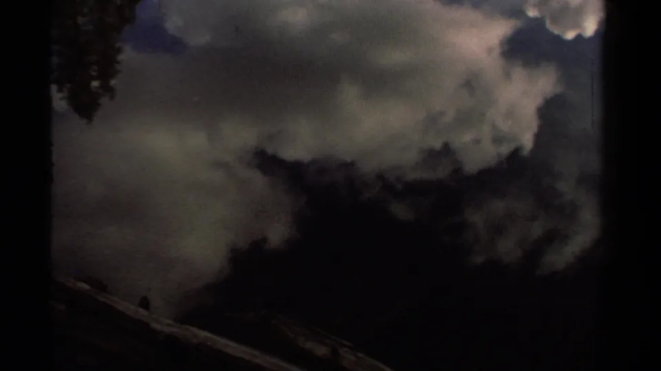 A darker 8mm frame of reflected clouds on Lake Tahoe water, with a diagonal fallen log visible near the lower frame edge.