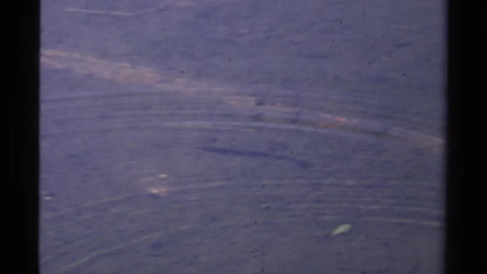 1978 Lake Tahoe 8mm frame showing rippled blue water, faint fish forms below the surface, and visible film wear.