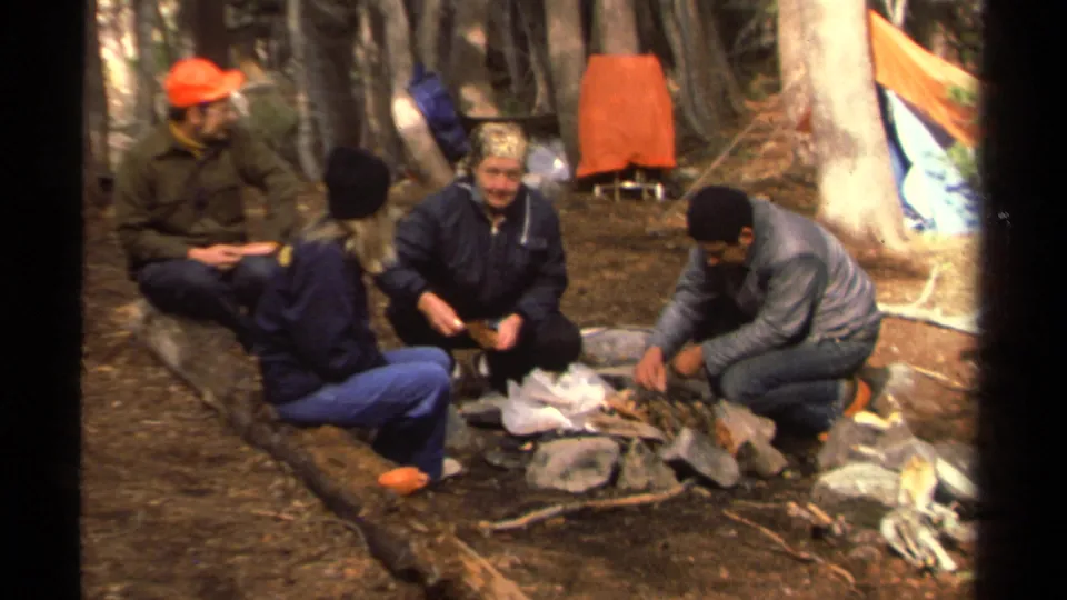 The closing frame shows four 1978 Lake Tahoe campers seated around a simple forest campsite with bags, sticks, logs, and an orange shelter.