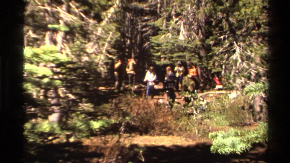 1978 Lake Tahoe 8mm frame showing a small group gathered in a pine forest clearing during an informal camping scene.