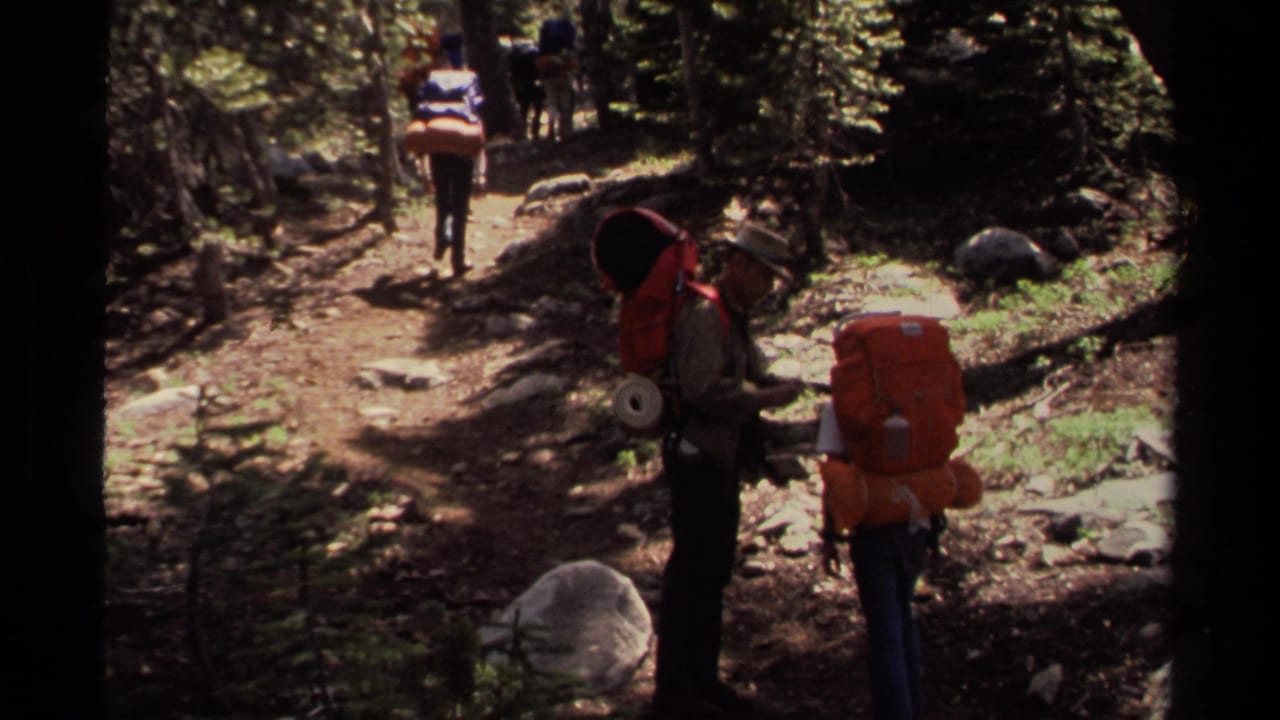 1978 Lake Tahoe home-movie frame showing several backpackers moving through a shaded conifer forest trail.
