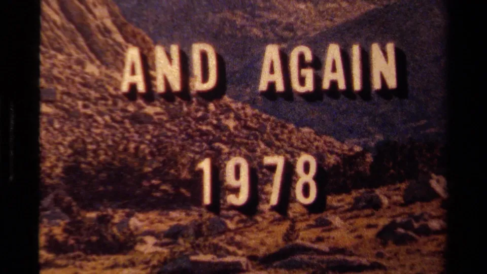 Lake Tahoe 1978 title card with white AND AGAIN lettering over rocky hills, mountain ridge, and blue sky on 8mm film.