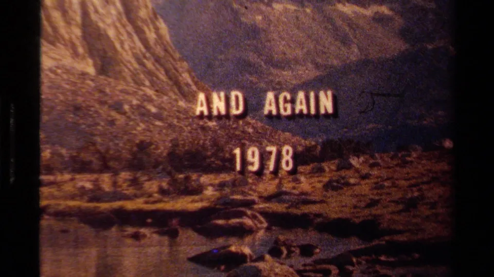 Lake Tahoe 1978 title frame with soft focus, visible grain, rocky slopes, and water at the bottom of the frame.