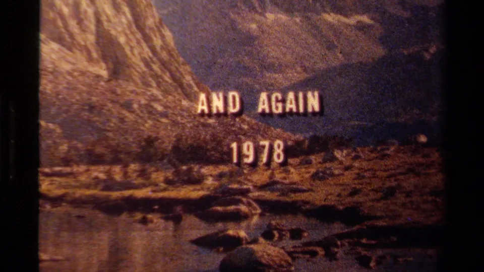 1978 Lake Tahoe home-movie title card reading AND AGAIN 1978 over water, shoreline rocks, and a steep mountainside.