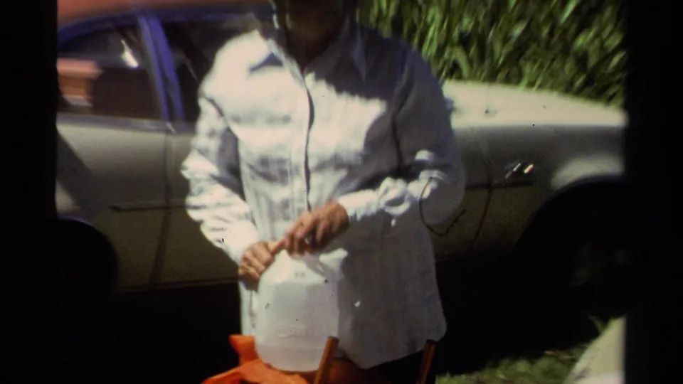 1978 Lake Tahoe frame showing an adult with a white water jug near a parked car during outdoor trip preparation.