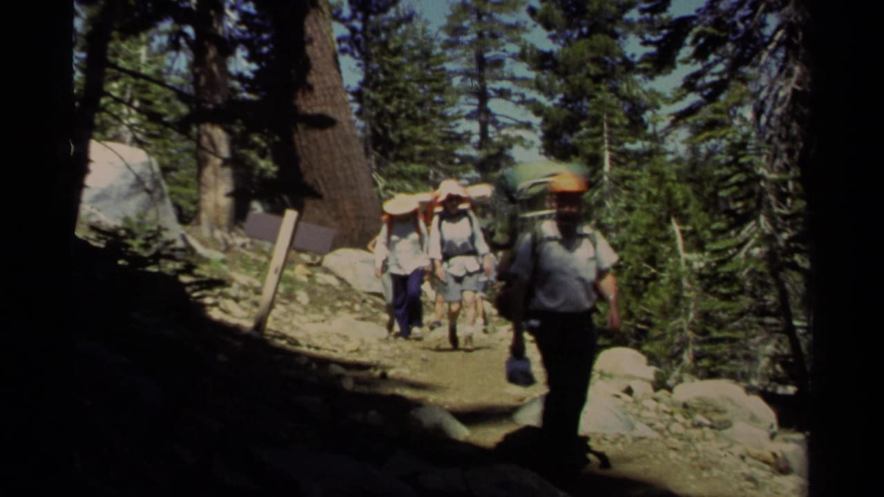 1978 Lake Tahoe trail scene with an orange-capped backpacker near the foreground and other hikers behind him.