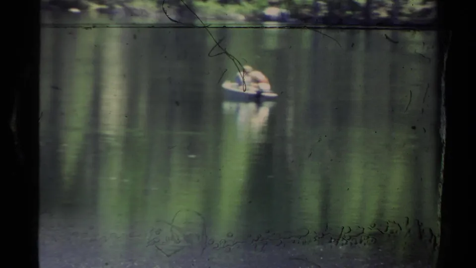 A 1978 Lake Tahoe frame shows a small boat with two distant people on green reflective water, with film scratches and frame edges visible.