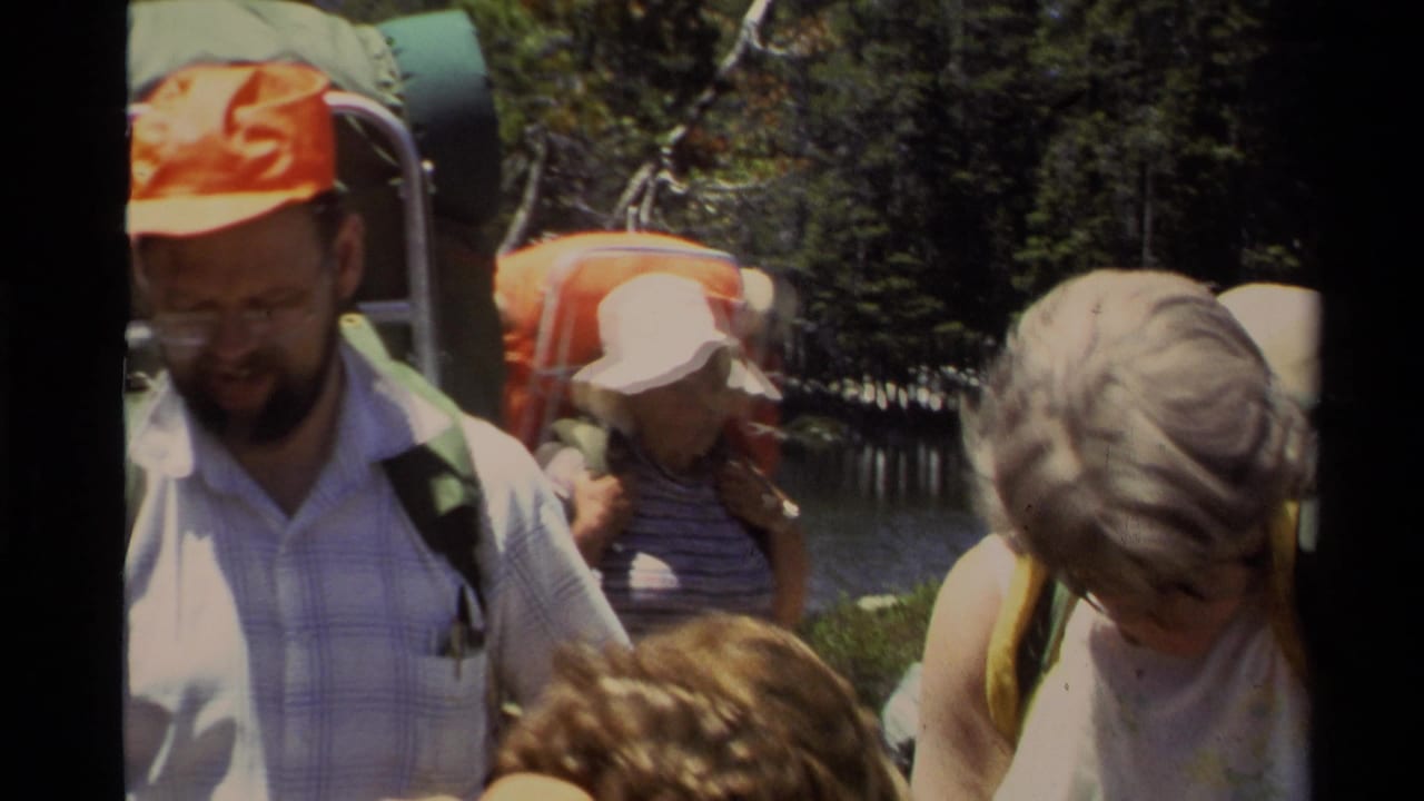 Adult hikers in 1978 Lake Tahoe footage gather with backpacks near a forested lakeshore.