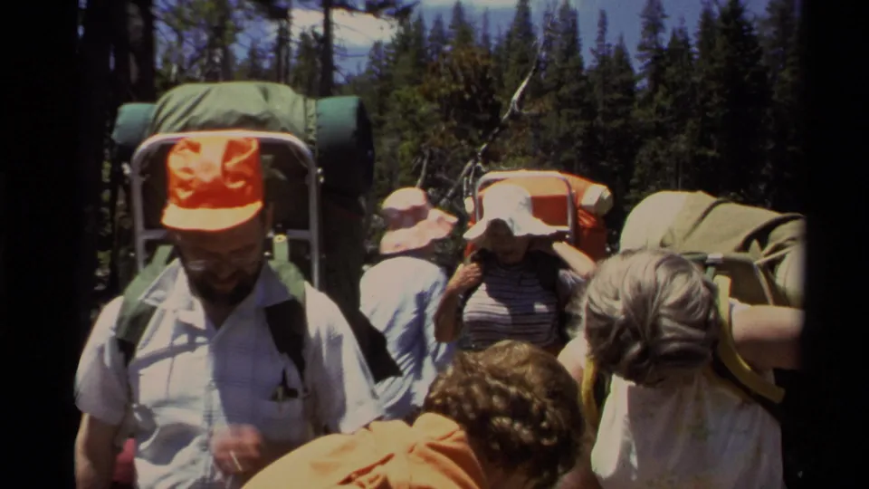 Lake Tahoe 1978 home-movie still of backpackers standing close to the camera along a wooded lakeshore.