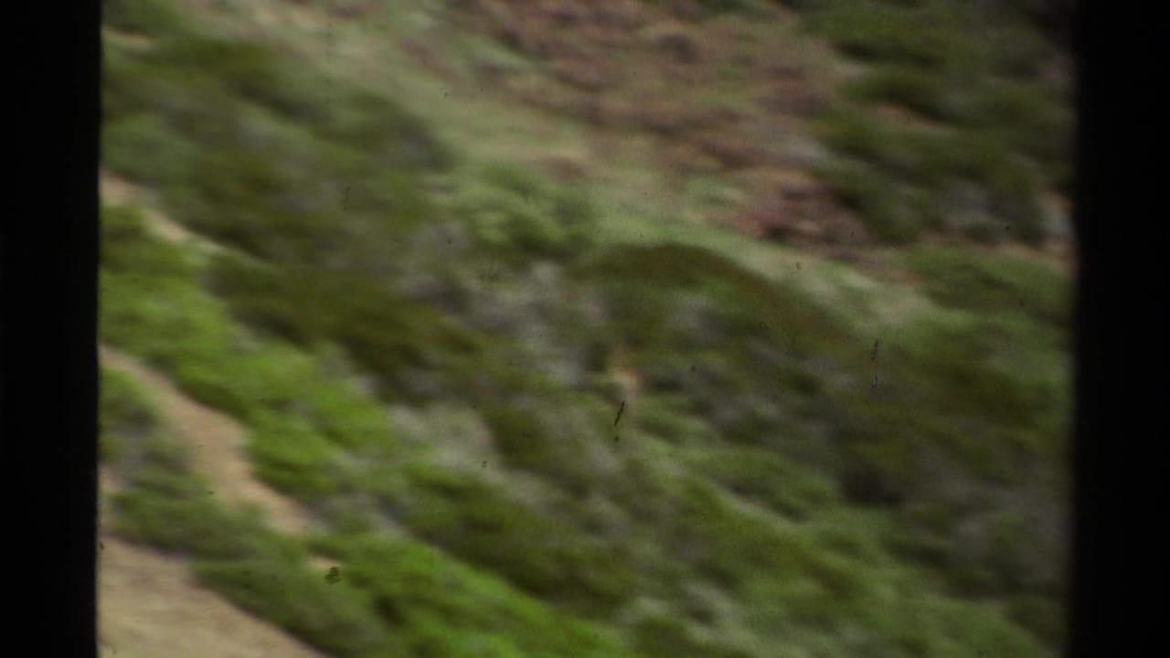 1978 Lake Tahoe home-movie frame of a green, rocky hillside with soft focus, motion blur, and dark gate edges.