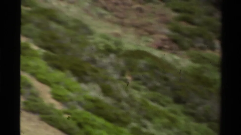1978 Lake Tahoe home-movie frame of a green, rocky hillside with soft focus, motion blur, and dark gate edges.