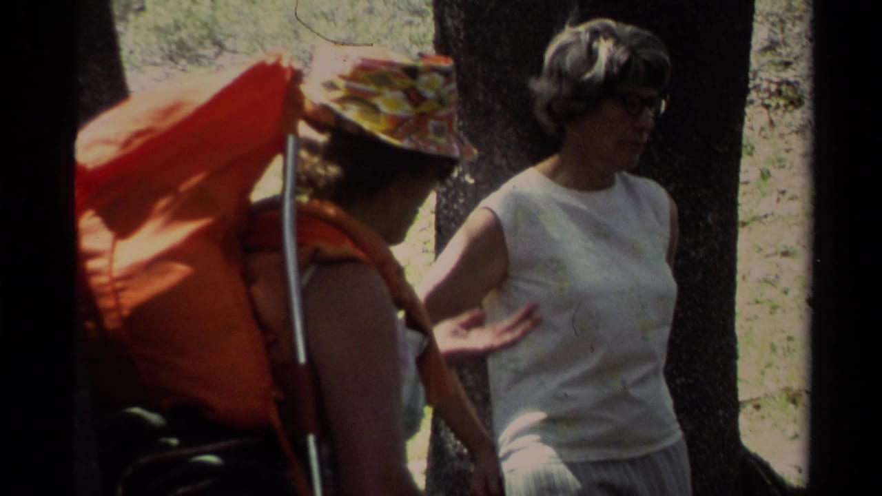 In 1978 Lake Tahoe home-movie footage, two adult women pause in woods with visible camping gear and dappled sunlight.