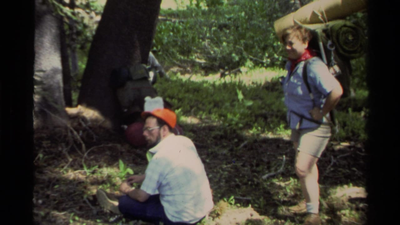 Lake Tahoe 1978 8mm frame showing a resting hiker seated under trees while another hiker stands with camping gear.