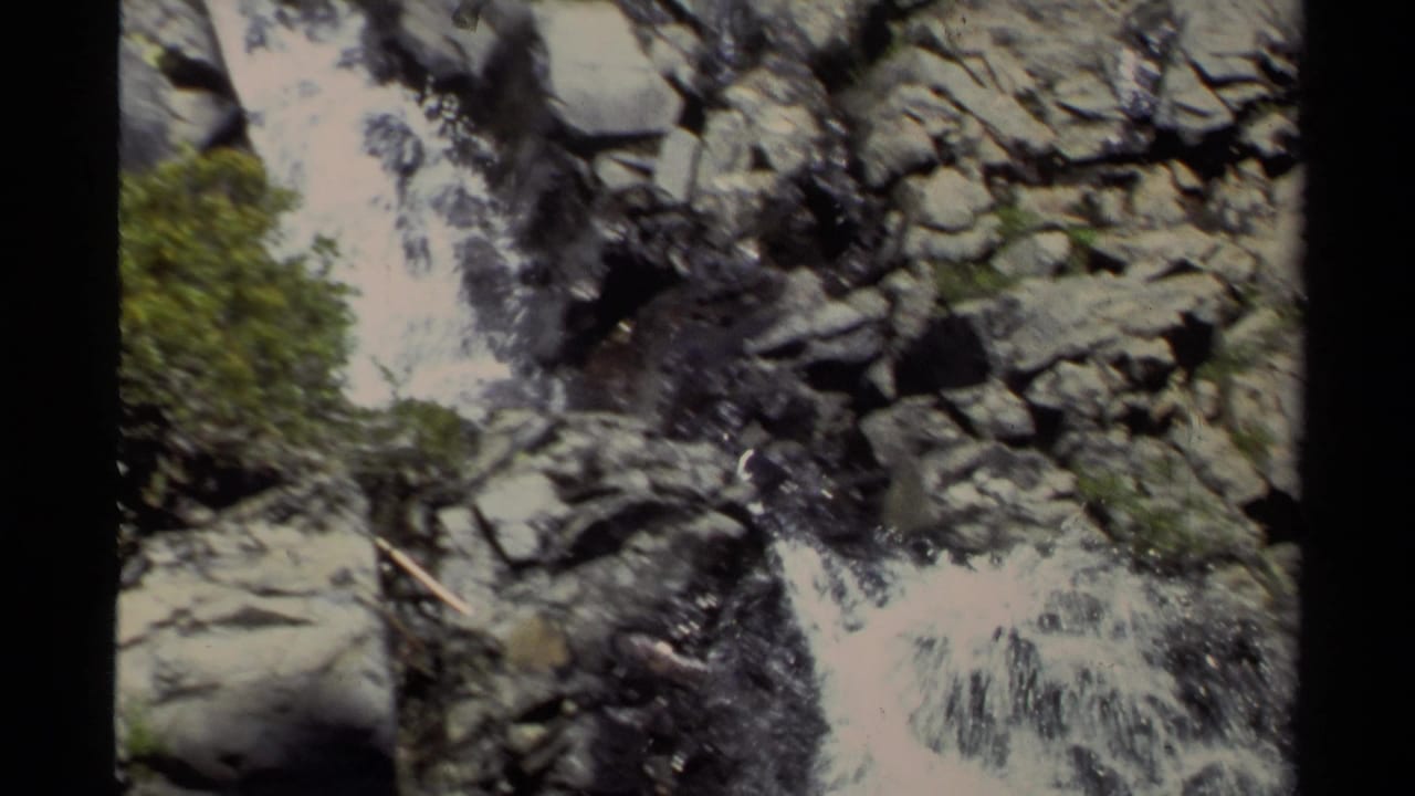 Lake Tahoe 8mm frame with white water cascading through gray boulders and green vegetation on a steep rocky slope.