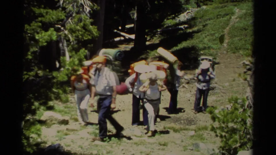 1978 Lake Tahoe 8mm frame showing a small group of adult hikers with large packs gathered on a dirt trail among pine trees.
