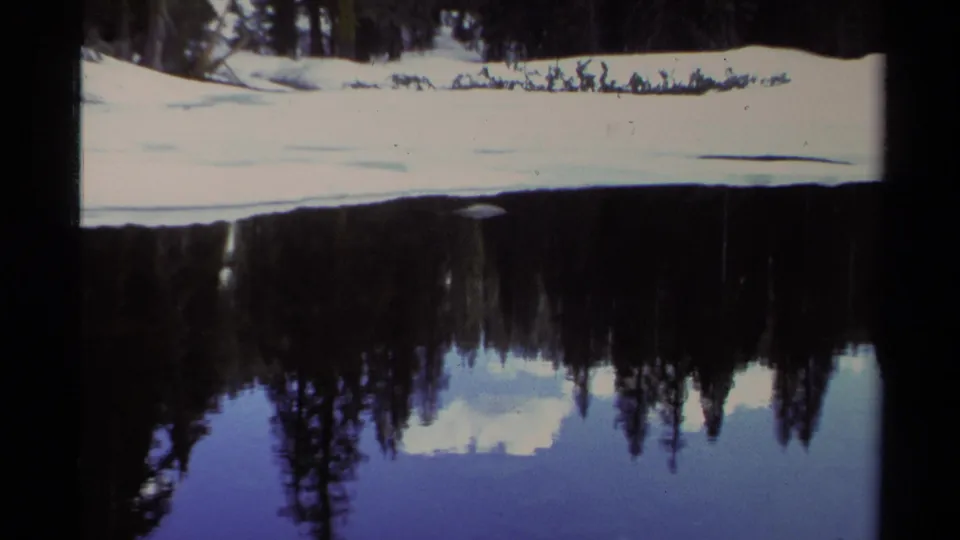 8mm Lake Tahoe frame with a snow-covered bank cutting across the scene and forest reflected below.