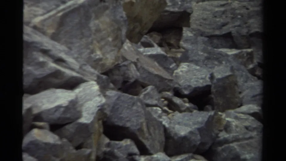 1979 British Columbia 8mm frame of clustered gray rocks on uneven ground, partly softened by low light and film grain.