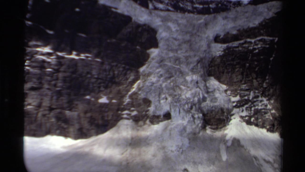 1979 British Columbia mountain view with textured glacier ice framed by dark cliffs and scattered snow.