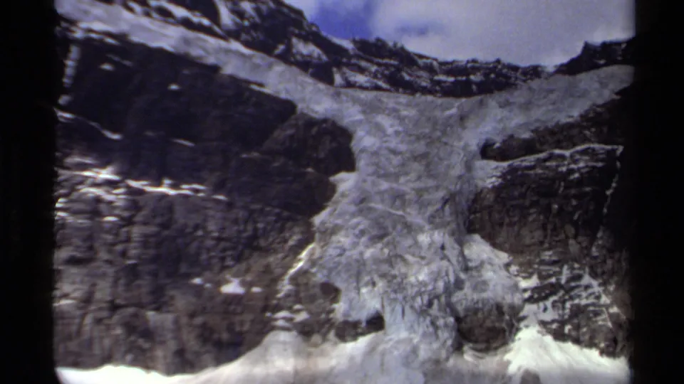 1979 British Columbia alpine frame showing glacier ice across a rugged mountain slope beneath a small opening of sky.
