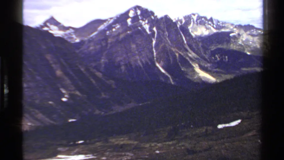 Final 1979 8mm view of a British Columbia mountain ridge, snowy gullies, forested valley, and visible film-frame border.