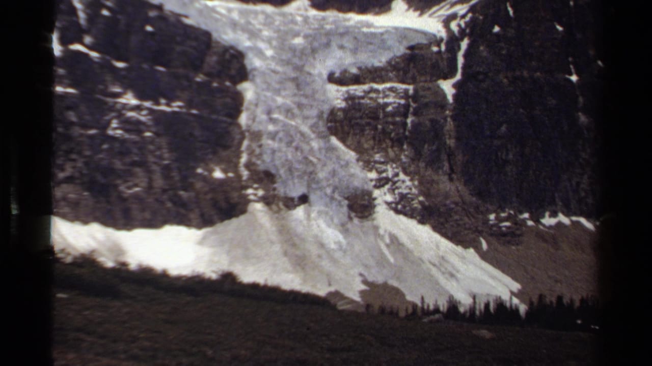 Rocky mountain face with broad snow patches and scree below.