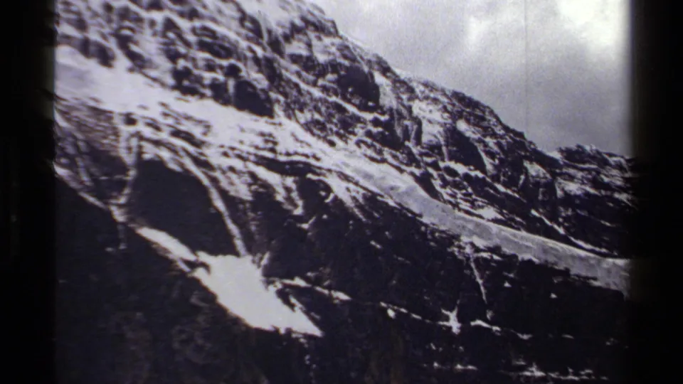 End of the pan across a British Columbia mountain ridge, with snow streaks, dark rock, and cloudy sky on 8mm film.