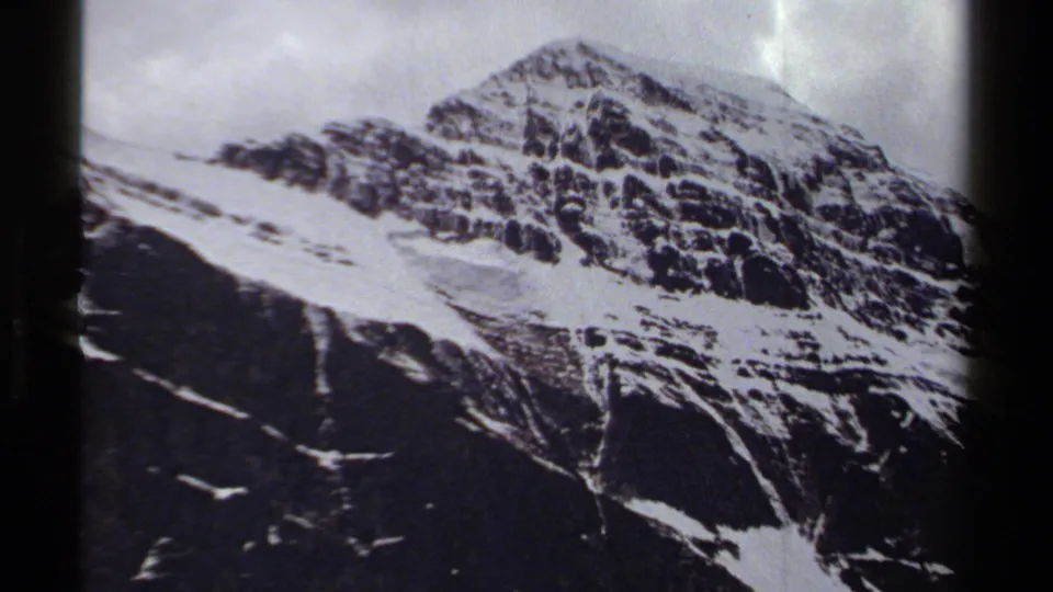 1979 British Columbia 8mm view of a steep alpine face, snow patches, and cloudy light across the ridge.