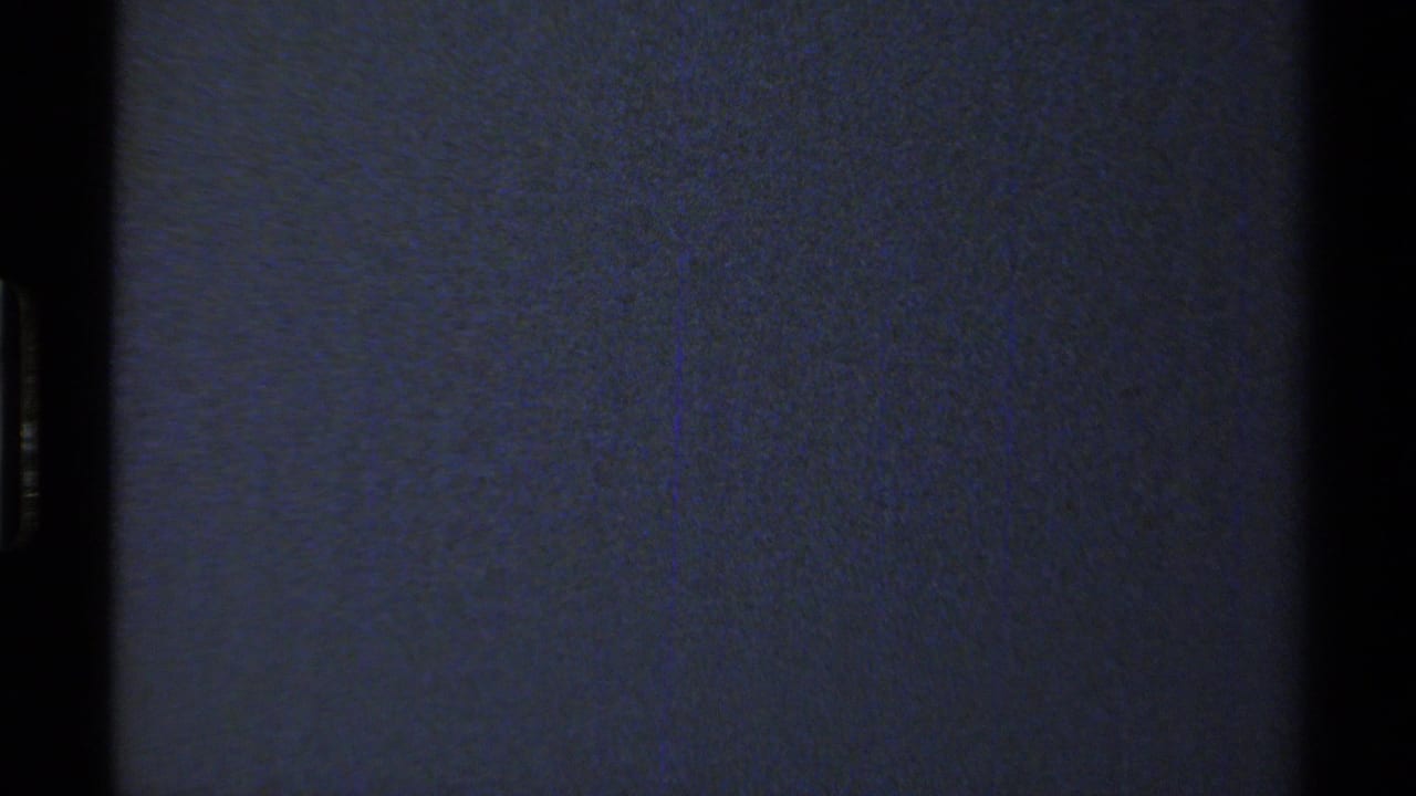 Underexposed 8mm frame showing mostly dark blue film texture with minimal discernible landscape detail.