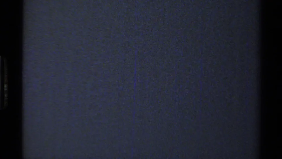 Underexposed 8mm frame showing mostly dark blue film texture with minimal discernible landscape detail.