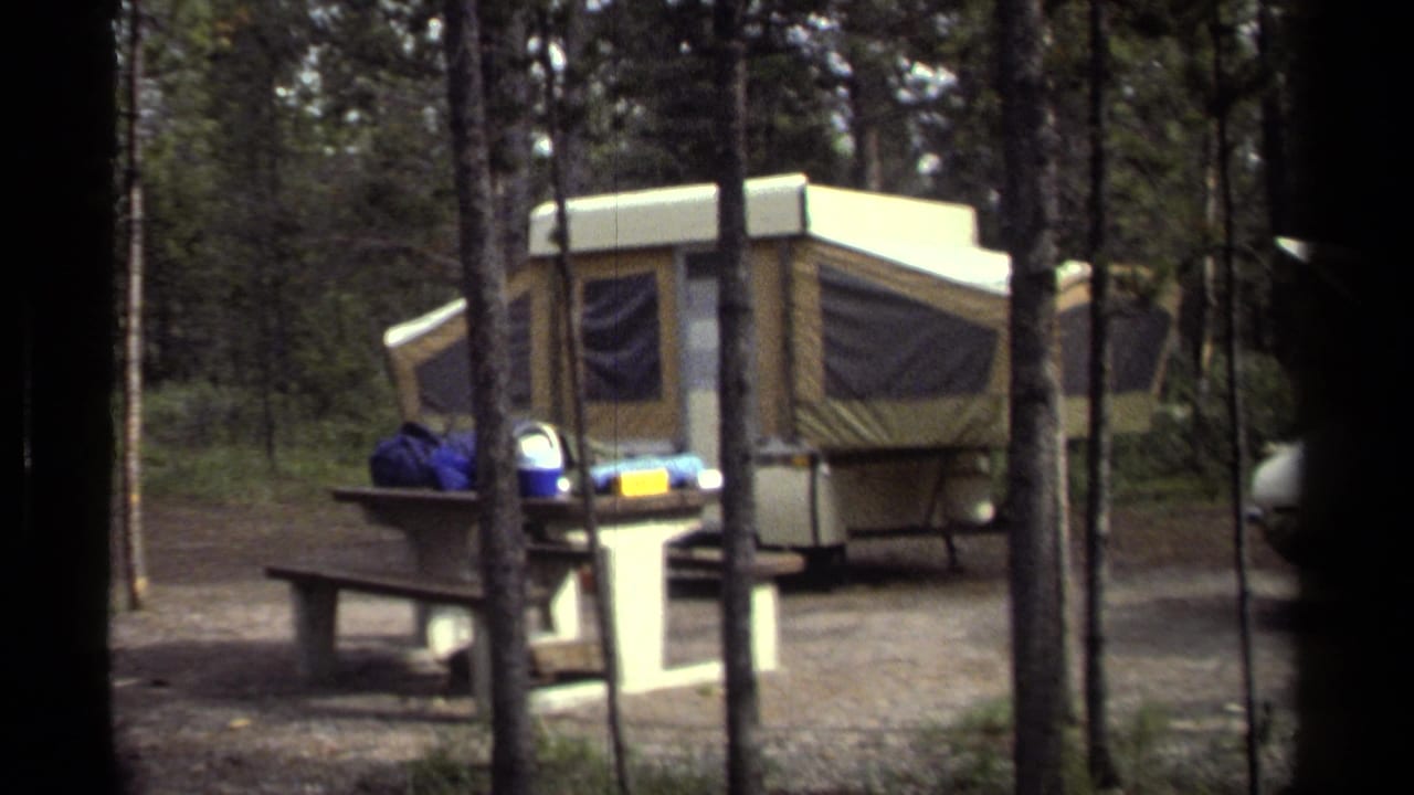 Wooded 1979 campsite frame with pop-up camper, picnic table, campsite post, and partial car at the edge.