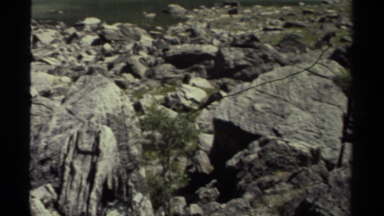 1979 8mm British Columbia footage showing rugged boulders, layered stone, sparse greenery, and dark frame borders during a landscape pan.