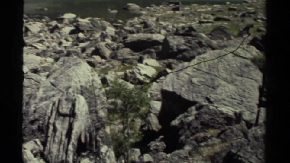 1979 8mm British Columbia footage showing rugged boulders, layered stone, sparse greenery, and dark frame borders during a landscape pan.