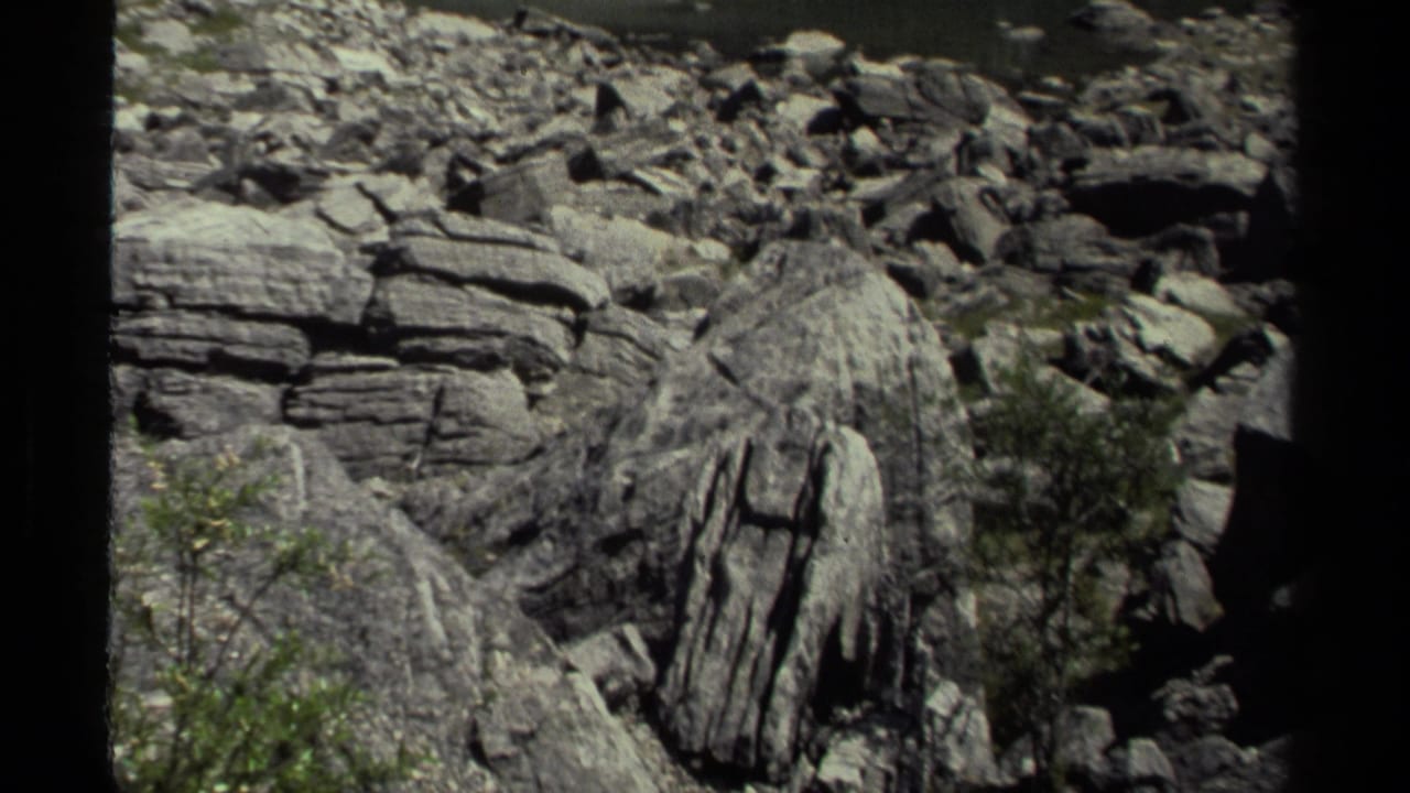 1979 8mm British Columbia footage continuing across a boulder field with layered rock faces, brush, and visible film-frame borders.