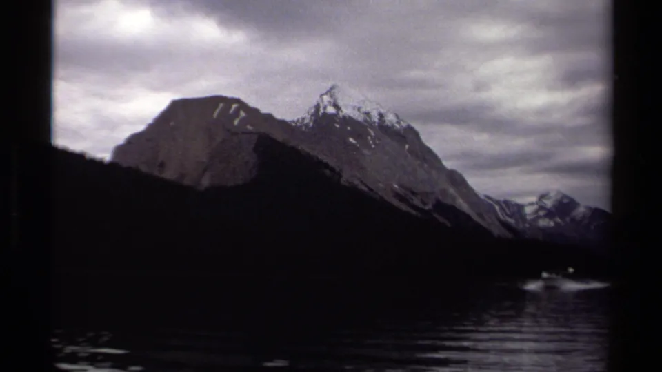 End frame of the 1979 British Columbia boat view, with a dark shoreline, rippled lake, rugged peaks, and overcast sky on 8mm film.