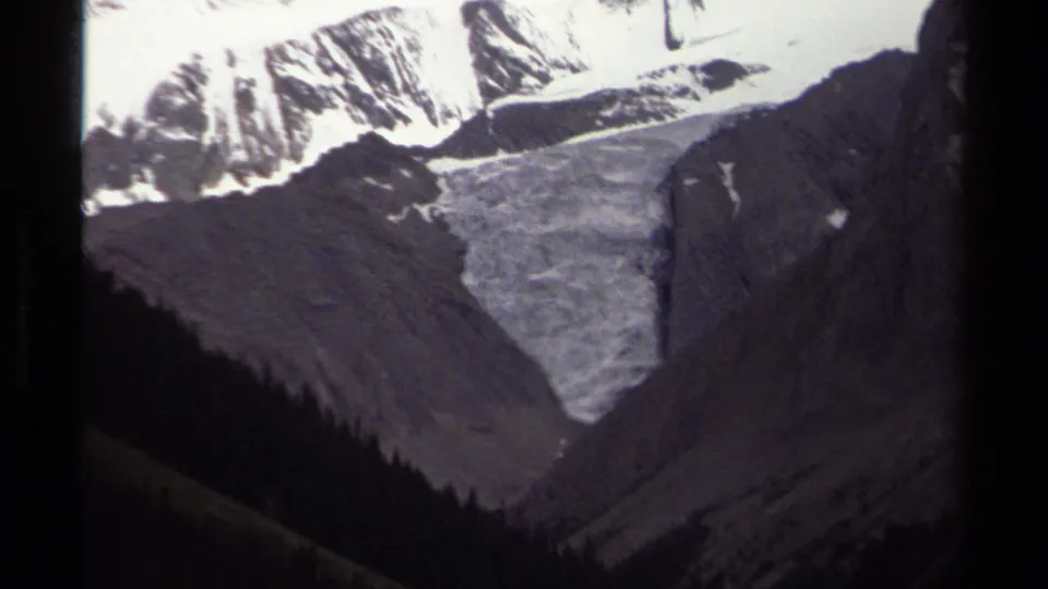 1979 British Columbia 8mm frame with the zoom moving closer to a pale glacier beneath rugged snow-capped peaks.