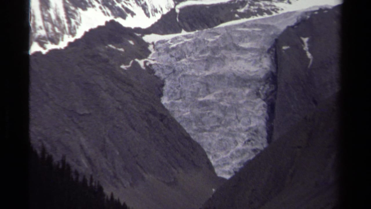 1979 8mm view of a glacier descending between rugged British Columbia mountain slopes under muted light.
