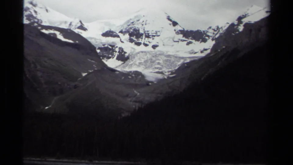 1979 British Columbia 8mm view of a glacier or snowfield set between rugged alpine slopes above dense forest.