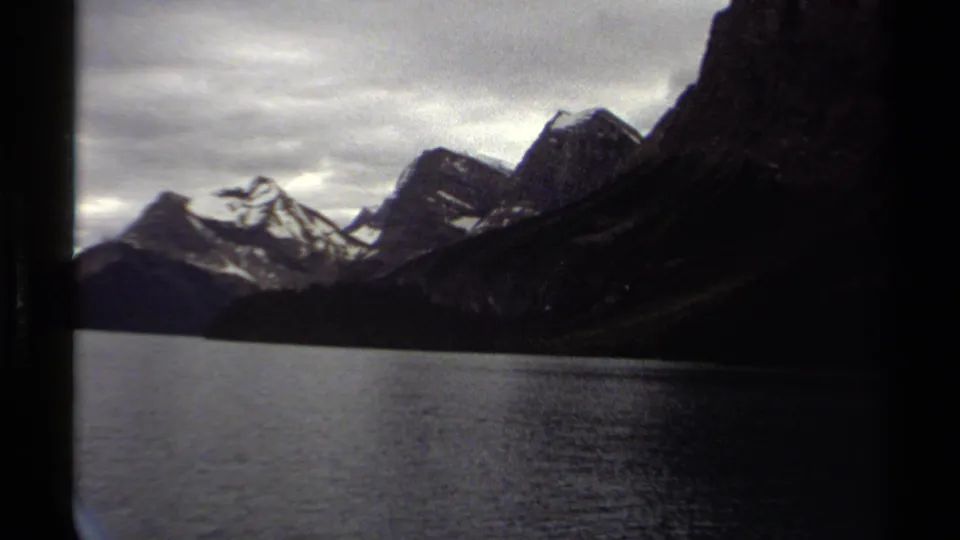 British Columbia lake and mountain range filmed on 8mm in 1979, with dark frame edges from the boat or film scan.