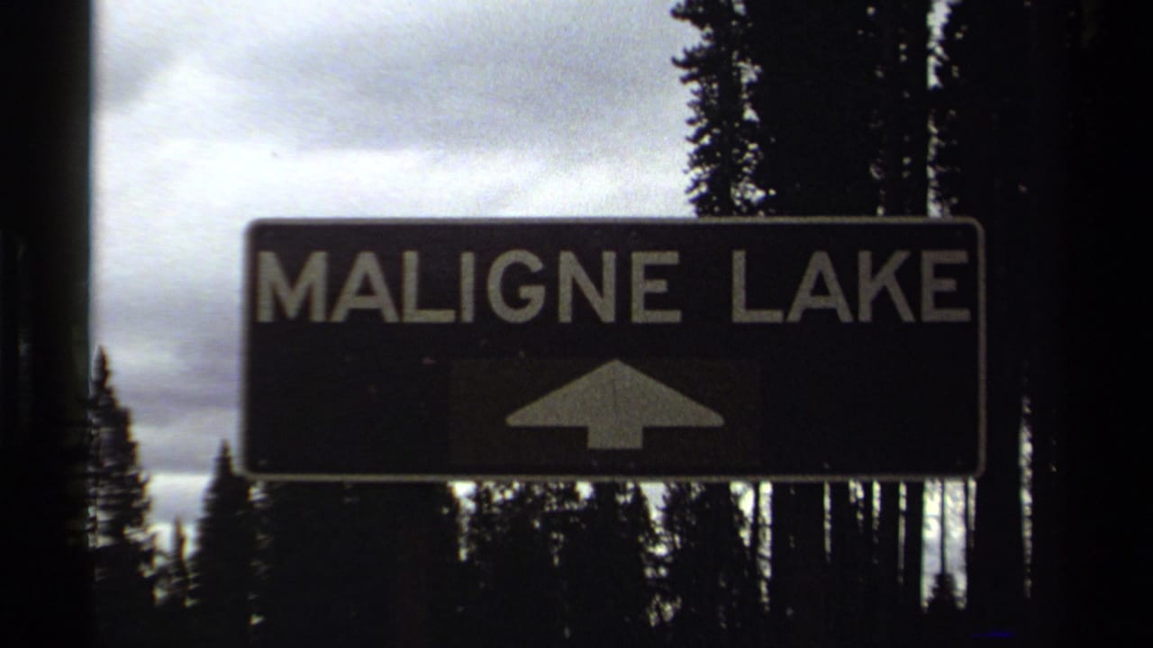 Cataloged 1979 8mm travel frame showing a Maligne Lake directional sign in front of tall evergreens under an overcast sky.