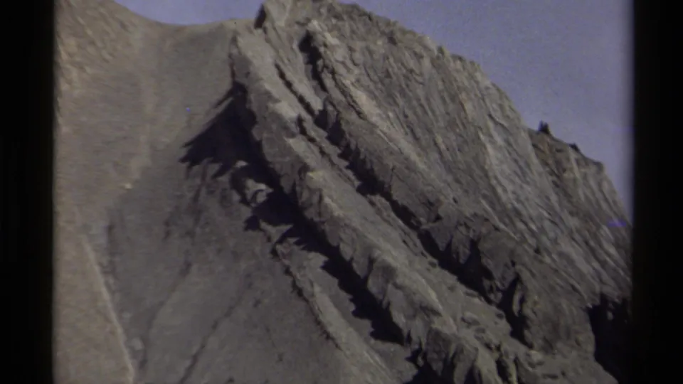 1979 British Columbia 8mm view of a rugged mountain slope, emphasizing rough rock layers and shadowed cuts.