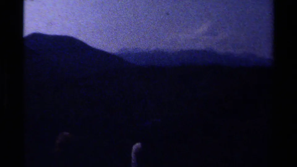Soft 8mm view of dark mountain and forest silhouettes, likely part of the same British Columbia hiking sequence.