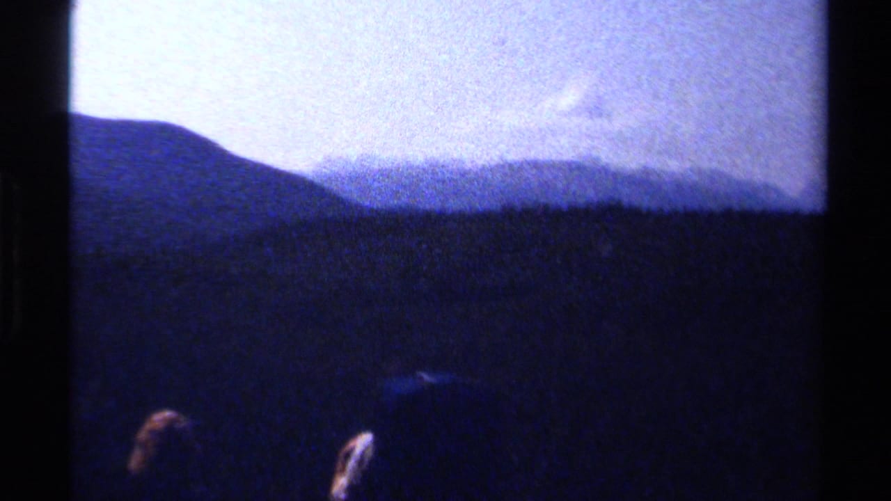 Dark mountain ridge under a pale sky with partial hikers at the lower edge.