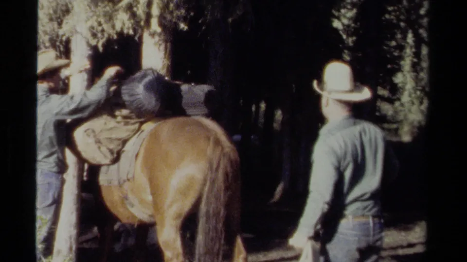 The final frame shows one man working near the horse's saddle while another man in a cowboy hat faces away among tall trees.